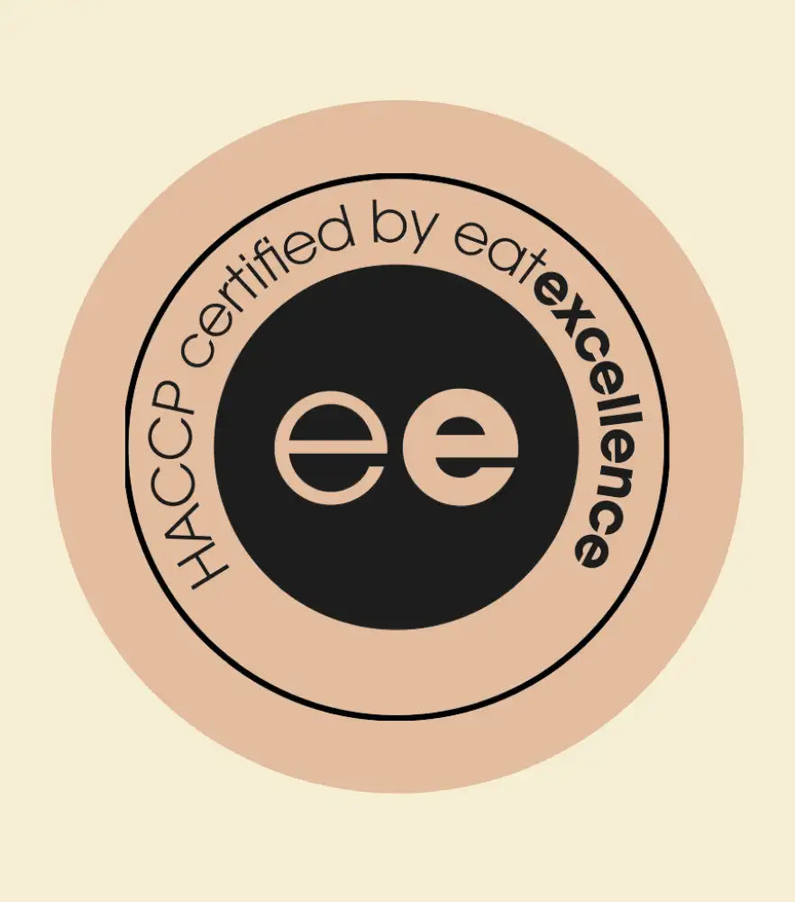 Ein kreisförmiges HACCP-zertifiziertes Logo von eatexcellence mit einem schwarzen Zentrum, das die Initialen „ee“ zeigt, und einem beigen Außenring.