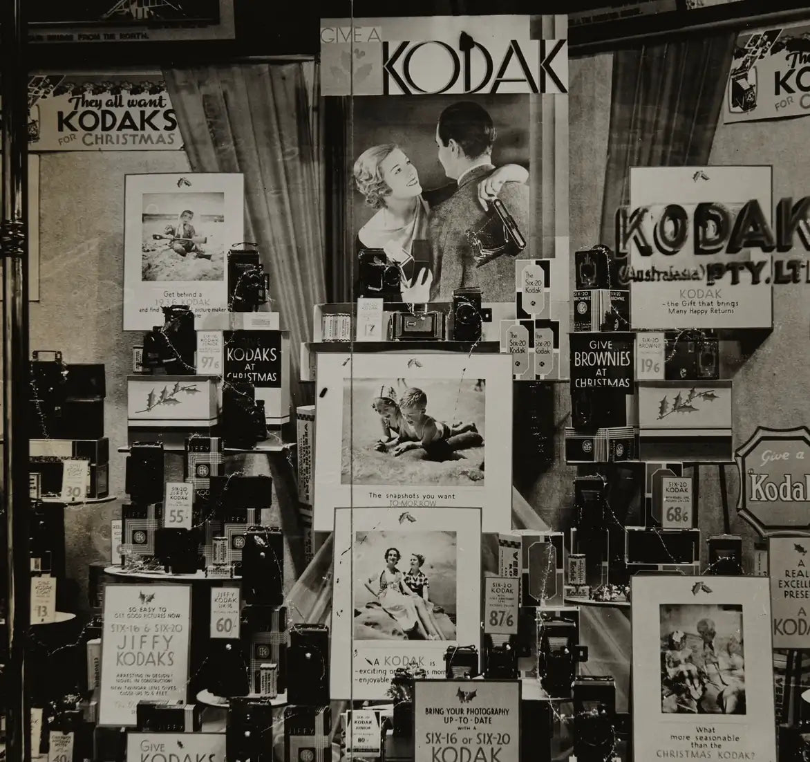 Vintage Kodak-Kameradisplay mit klassischen Schwarzweiß-Werbeplakaten und verschiedenen Filmkameras.
